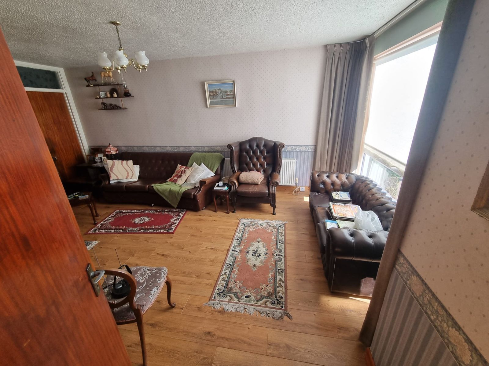 A sitting room in a family home, furnished and full of belongings, before a clearance
