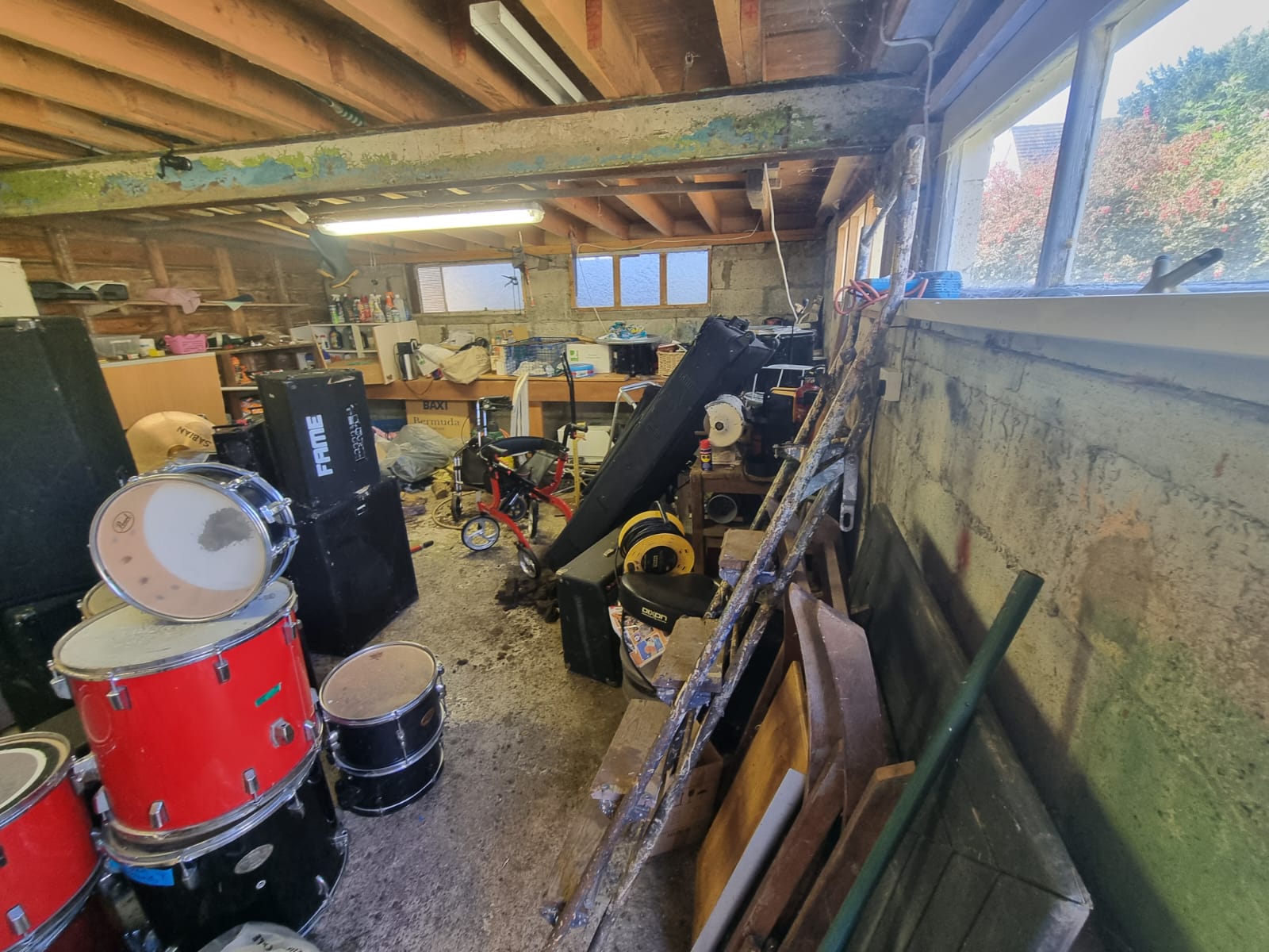 A cluttered garage full of tools and furniture before clearance