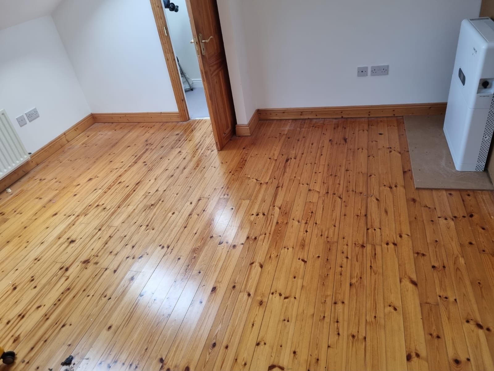 A bright, empty room with polished wooden floorboards after a house clearance