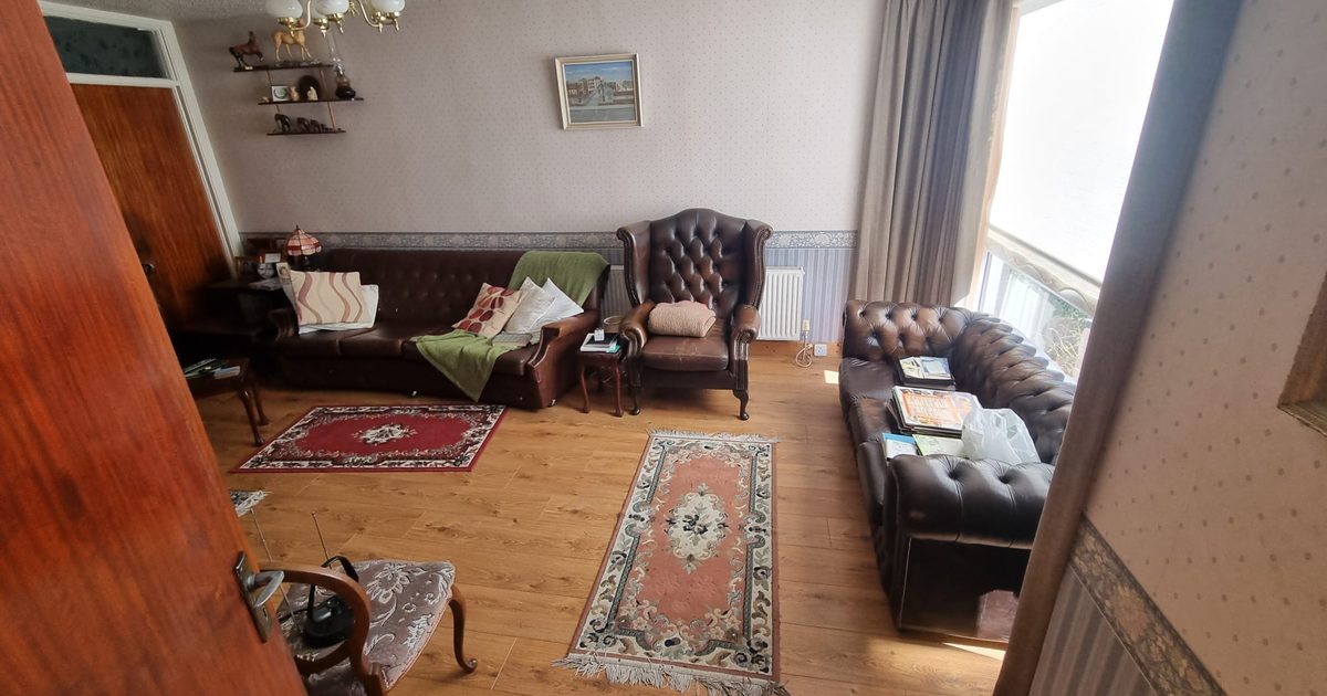 A sitting room in a family home, furnished and full of belongings, before a clearance