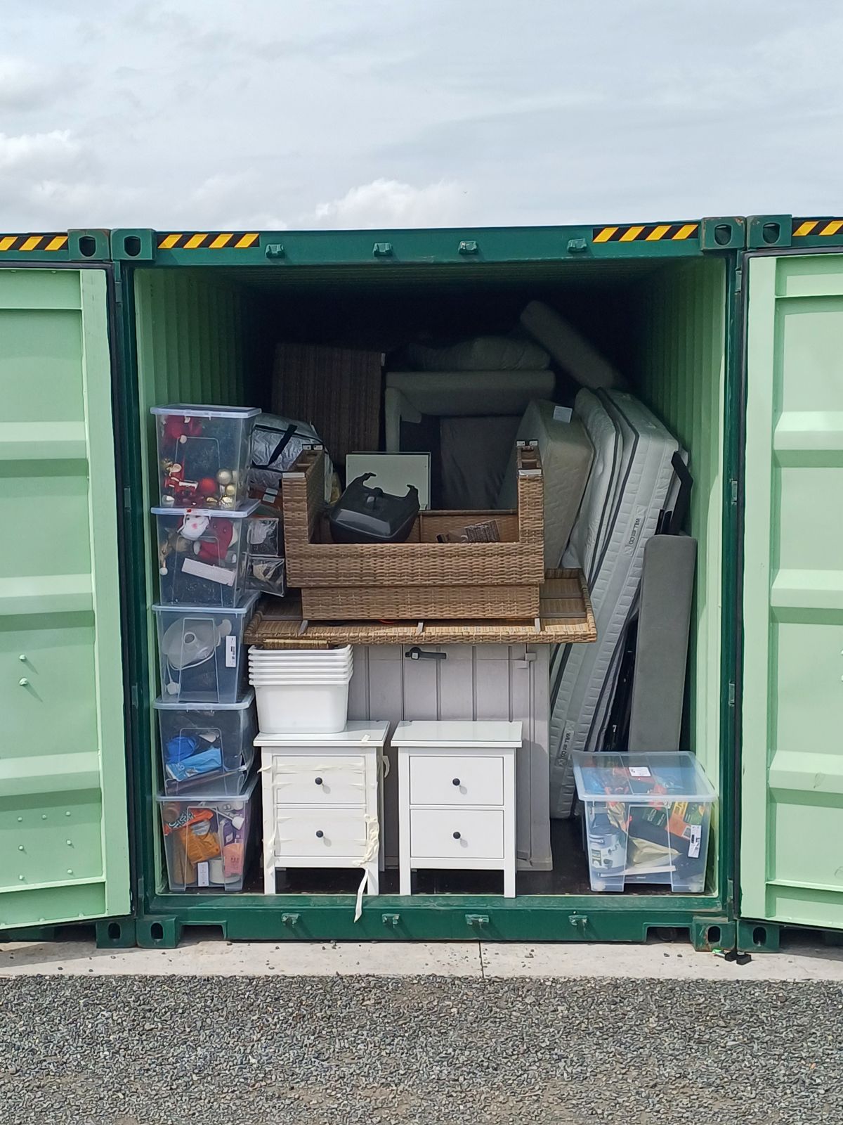 An open storage container packed with furniture, bedside lockers and boxes of belongings